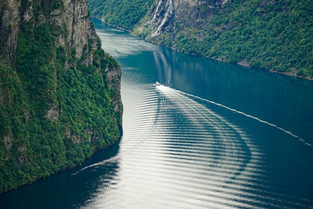 Steep green fjord walls meeting still water in Norway